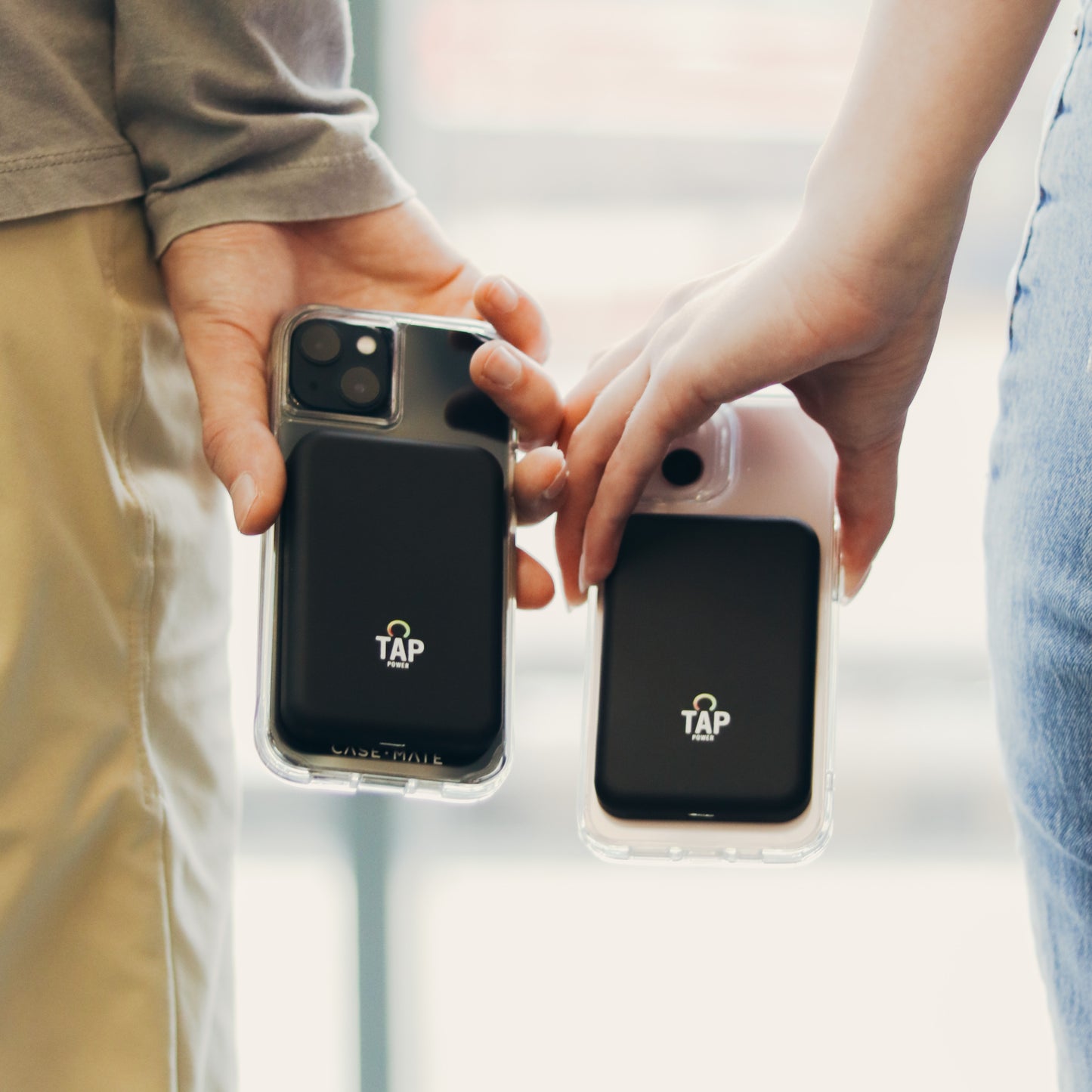 Two Tap Power Reserves being held by a male and female couple. The Reserves are magnetically attached to their iPhones and are simultaneously being charged.