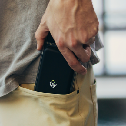 Tap Power's slim design being displayed as a person slips an iPhone with a Reserve attached into their pocket.